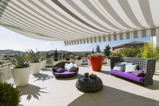 Terrasse moderne avec mobilier d'extérieur haut de gamme sous store banne rayé